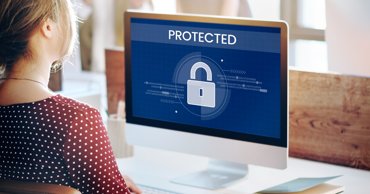 woman working at computer with a lock graphic on monitor displaying protection